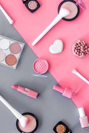Makeup background with rounge, powder and tools on pink and grey table top view.の写真素材
