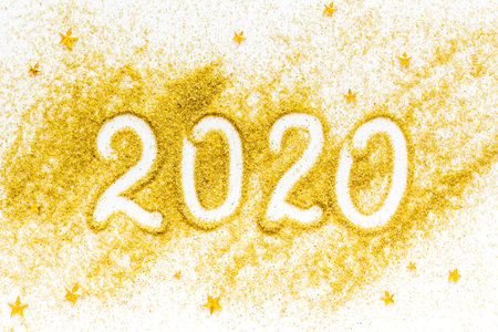 2020 Happy New Year. Date written on golden dust on white background top view