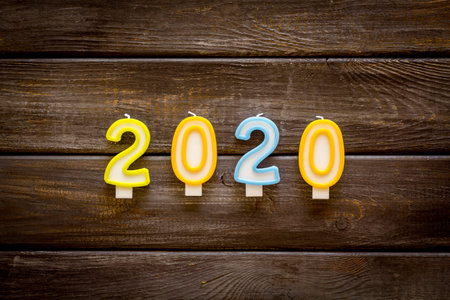 2020 New Year card. Candles on dark wooden background top view.