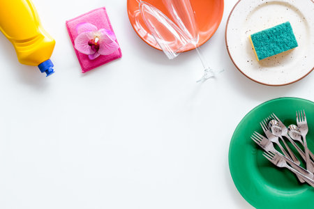 Washing dishes frame with plates, sponges, dishwashing liquid on white background top view space for...