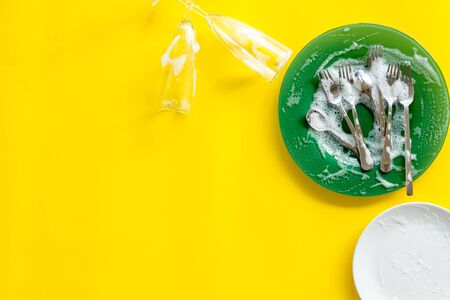 Washing dishes concept. Plates, spoons, forks on yellow background top view.の写真素材