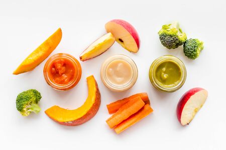 Baby food. Colorful puree in glass jars near vegetables and fruits on white background top view.の写真素材