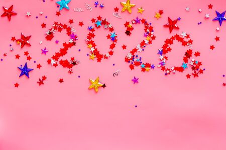 Celebrate New Year 2020. Date on confetti near champagne bottle on pink background top view.の写真素材