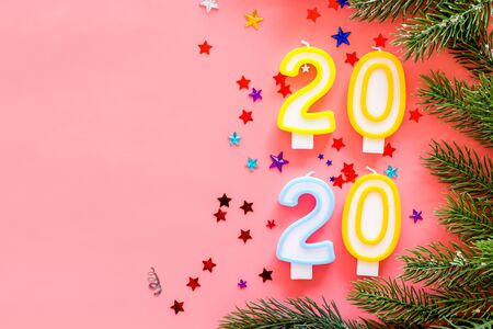 2020 New Year design. Date laid out by candles near fir branches on pink background top view.の写真素材