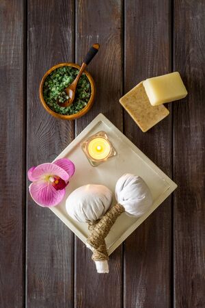 Preparing for massage in spa salon - with candles and orchids - dark wooden background top view patternの写真素材