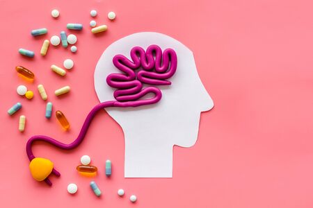 Brain charging and mental rest. Plug and cable leads to plastiline meanders on pink background top view.の写真素材