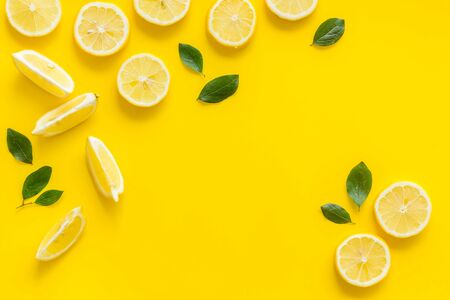 Fruit frame. Lemons and leaves on yellow background top view copy spaceの写真素材