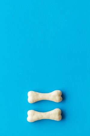 Food and toys for dogs. Chewing bones on blue background top view copy space