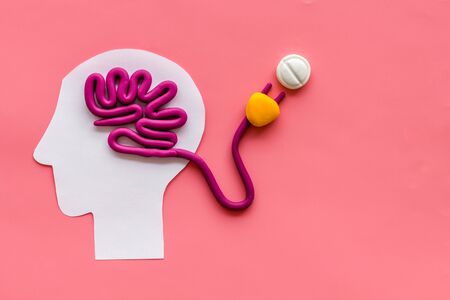 Brain charging and mental rest. Plug and cable leads to plastiline meanders on pink background top view.の写真素材