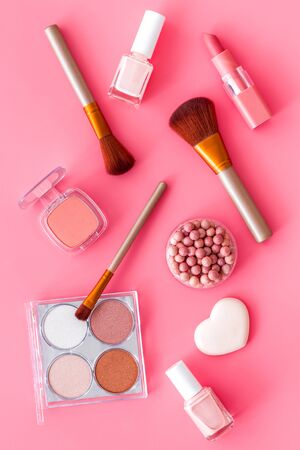 Makeup background with rounge, powder and tools on pink table top viewの写真素材