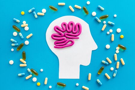 Treat brain diseases. Head with plastiline meanders and pills on blue background top viewの写真素材