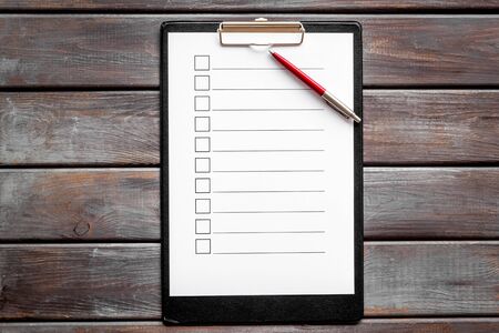 Empty check list ready to fill on dark wooden background top view.の写真素材