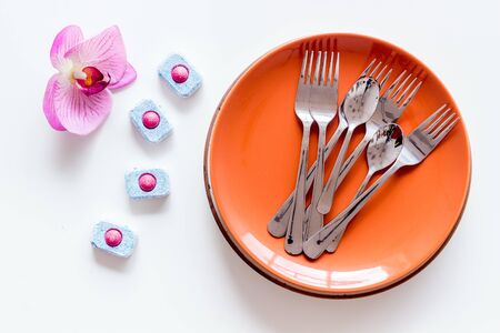 Dry detergent for dishwashing near plates and orchid flower on white background top viewの写真素材
