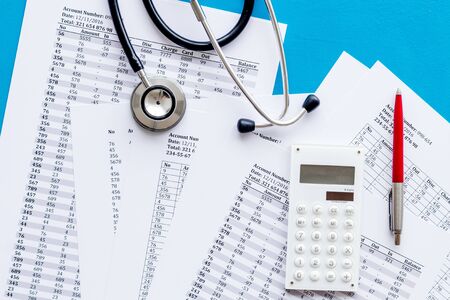 Health insurance concept. Stethoscope near financial documents and calculator on blue background top viewの写真素材
