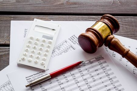 Taxes debt concept. Judge hammer near financial documents on dark wooden background.の写真素材