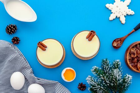 Ingredients for New Year drink eggnog - eggs, milk, cinnamon on blue background top view.の写真素材