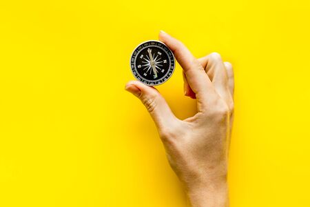 Choose direction concept. Compass in hand on yellow background top view.の写真素材