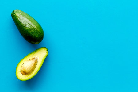 Avocado - whole and halfs - frame on blue background top view copy space