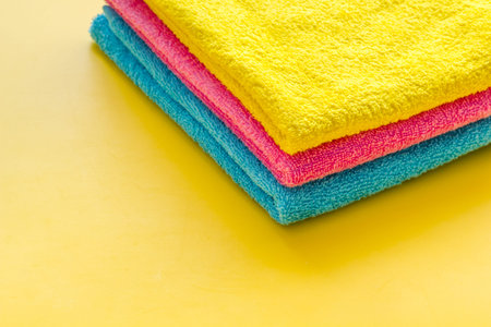 Clean towels - stack of laundred linen - on yellow background copy space