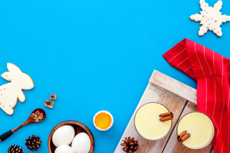 Ingredients for New Year drink eggnog - eggs, milk, cinnamon on blue background top view frame copy...