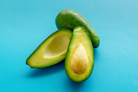 Avocado - ripe and bright, cutted in half - on blue background closeup