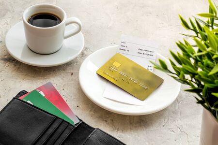 Paying in restaurant. Bank card near cup of coffee on grey tableの写真素材