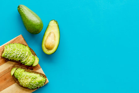 Healthy food. Avocado toast on blue background top view frame copy space