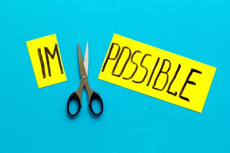 All is possible concept. Cut word impossible near scissors on blue background.の写真素材