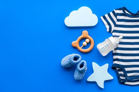 Newborn baby boy blue clothes as bodysuit, booties, toys on blueの写真素材
