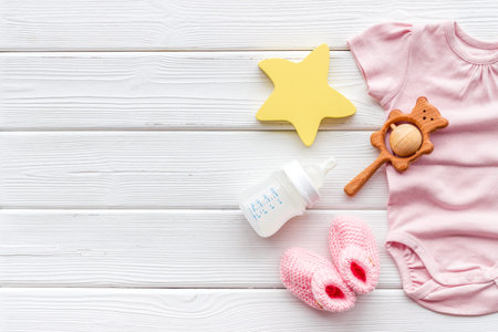 Baby background - pink color. Clothes, booties and accessories for newborn girl on white wooden...