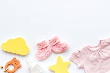 Newborn girl set - clothes as bodysuit, booties, toys - on white table top-down frame.の写真素材