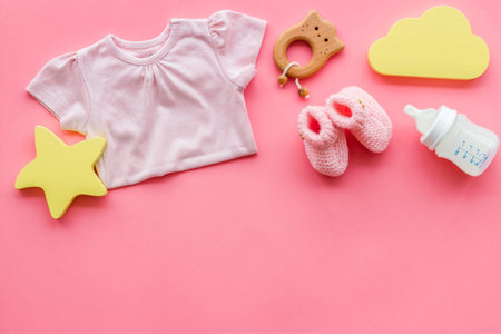 Baby background - pink color. Clothes, booties and accessories for newborn girl on pink table...