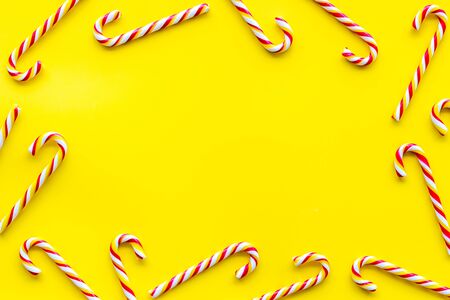 Christmas candies frame - cane with red and white stripes - on yellow background top-down.の写真素材