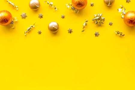 New Year decoration background - golden balls and bows on yellow desk top-down frame copy spaceの写真素材