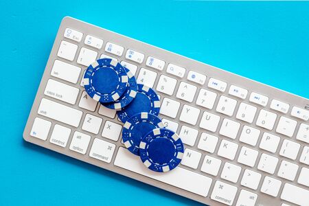 Online poker. Chips near keyboard on blue background top-down.の写真素材