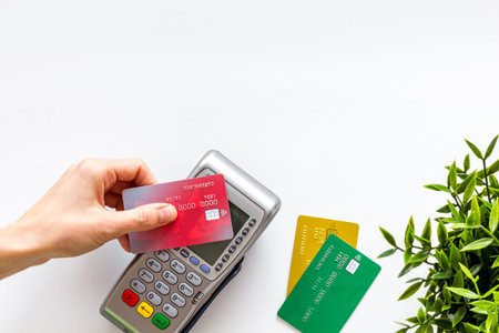 Contactless payment, paypass. Hand hold bank card near terminal on white background top-down.