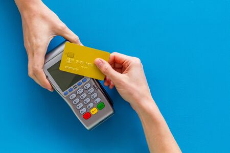 Contactless payment, paypass. Hand hold bank card near terminal on blue background top-down.の写真素材