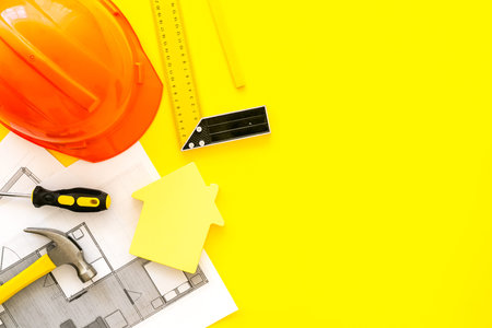Construction concept. Helmet, instruments, blueprints on yellow background top-down.
