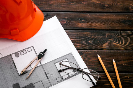 Construction concept. Helmet and blueprints on dark wooden background.