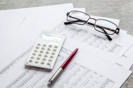 Taxes calculation concept. Financial documents, calculator, glasses on grey backgroundの写真素材