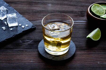 Whiskey near ice cubes on dark wooden background.の写真素材