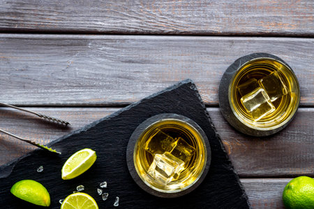 Bar background with whiskey and ice on dark wooden desk top-down frame copy spaceの写真素材