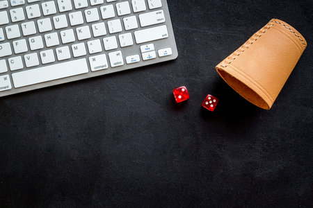 Hazard gemes online concept. Dices near keyboard on black background top-down.
