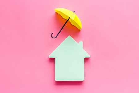 House cutout under umbrella on pink backgound top view copy spaceの写真素材