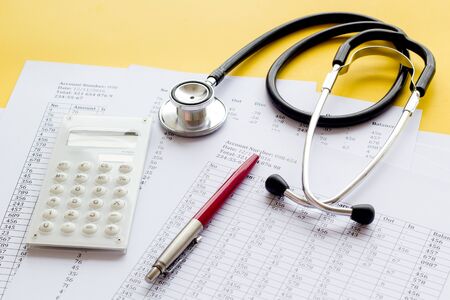 Health insurance concept. Stethoscope near financial documents and calculator on yellow background.の写真素材