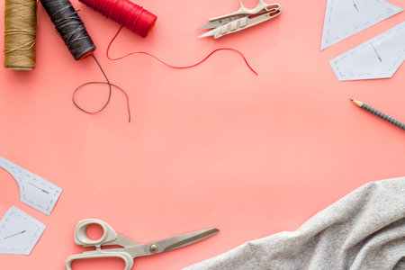Sewing wokrshop. Textile, pattern, scissors, thread on pink background top-down.