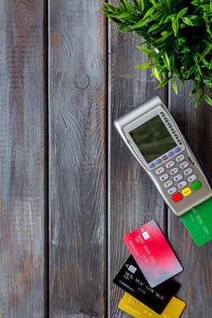 Pay by card. Plastic card inserted in terminal on dark wooden background top-down copy spaceの写真素材