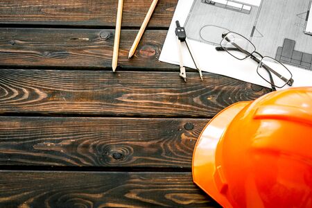 Construction concept. Helmet and blueprints on dark wooden background copy spaceの写真素材