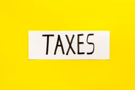 Taxes text on yellow background top viewの写真素材