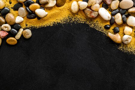 Resort or vacation concept. Sea stones and sand on black background top-down frame.の写真素材